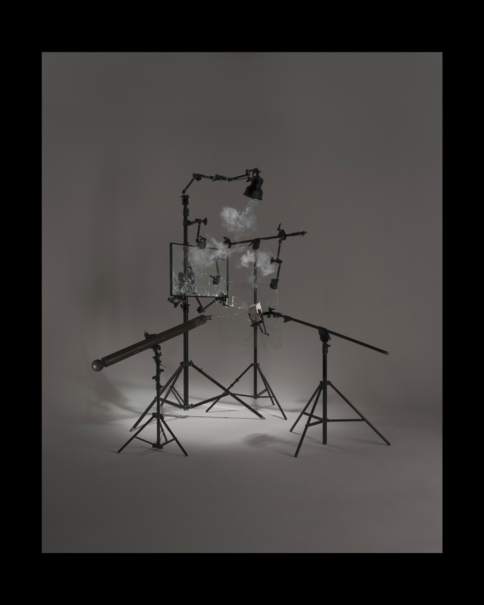 Par Thomas Taz Cecchelani : photographie d’une installation. Cette structure est composée de matériel photographique et urbain. Elle est pensée comme ordonnée. Elle supporte des vitres brisées, un pavé et un poteau de rue. Cette installation fait référence à la destruction des vitrines publicitaires. Elle exprime le refus de la représentation photographique, que l’on décrit souvent en miroir du réel. Cette installation est éclairée puis photographiée. Reste une image artificielle, au rendu proche de la publicité. Il s’agit d'interroger les formes possibles de représentation photographique d’un événement par le recours à la fiction.